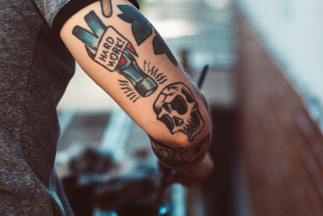 Tattoo industry. Back of man's arm with tattoo - hammer and skull