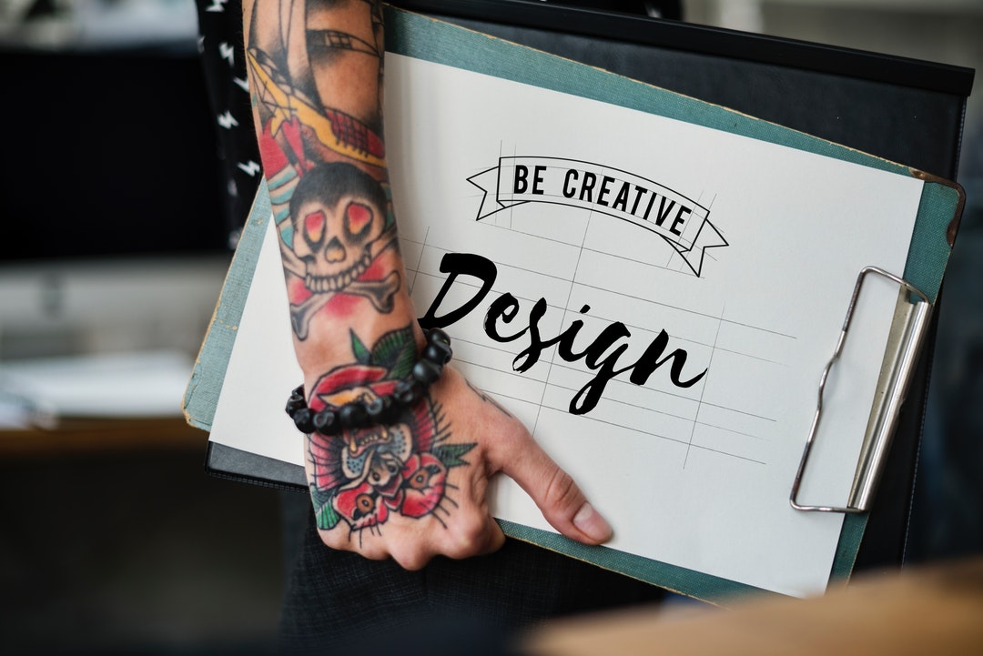 tattoo fonts - person with tattooed arms holding green a drawing book
